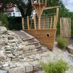 Man sieht ein Baumhaus in Form des Bugs eines Holzschiffs. Es hat im Bauch des Schiffes ein Bullauge und auf dem Deck ein Krähennest. Ein Traum für jeden Nachwuchs-Piraten.