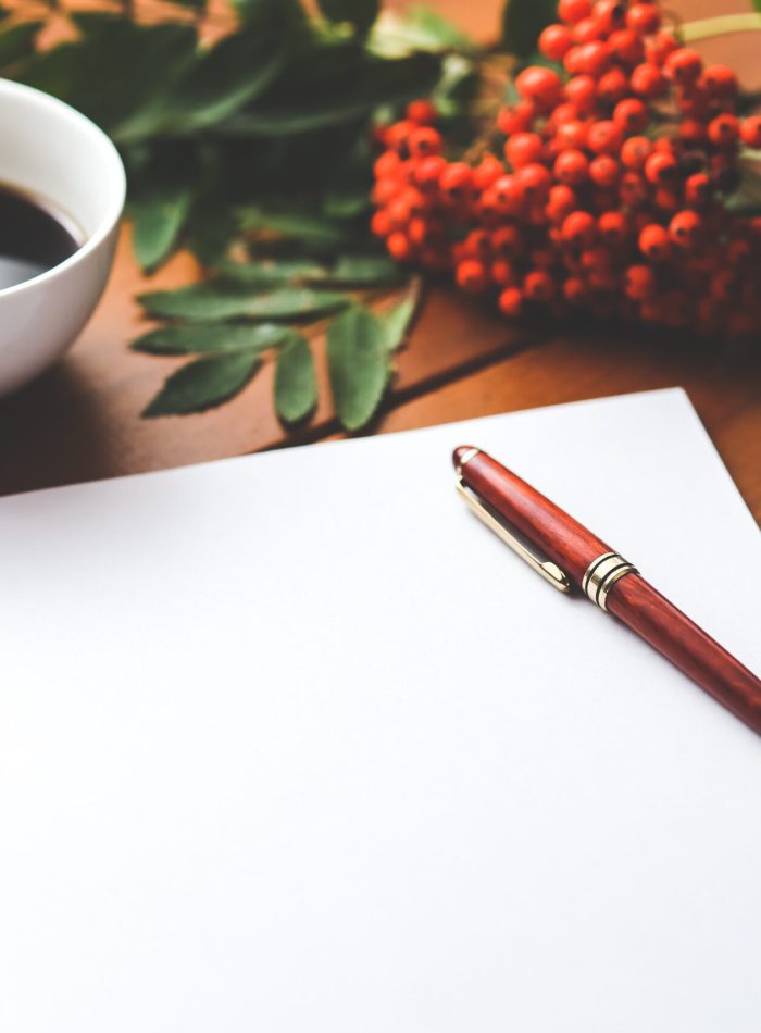 pexels-kaboompics-com-6357 Ein weißes Blatt Papier für die Planung von Grünrausch-Jena Projekten, darauf liegt ein Stift. In der oberen linken Ecke des Bildes sieht man eine Tasse Kaffee. In der oberen rechten Ecke des Bildes sieht man einen Zweig von einer Eberesche mit roten Vogelbeeren.